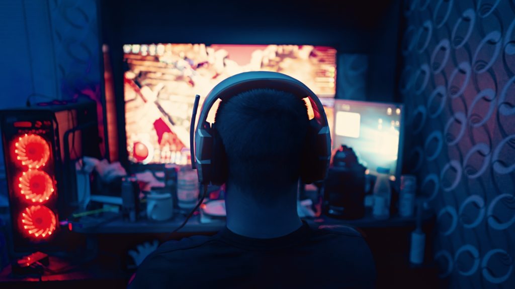 Osoba grająca na komputerze w słuchawkach