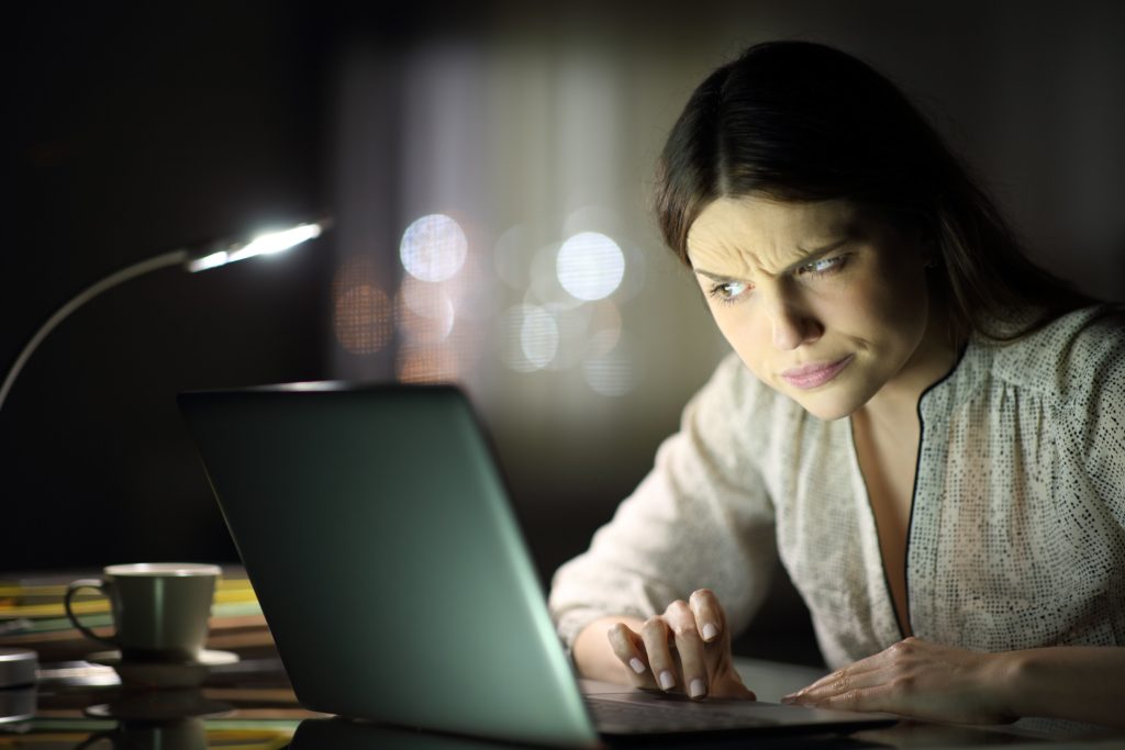 kobieta podejrzliwie sprawdza dane na laptopie