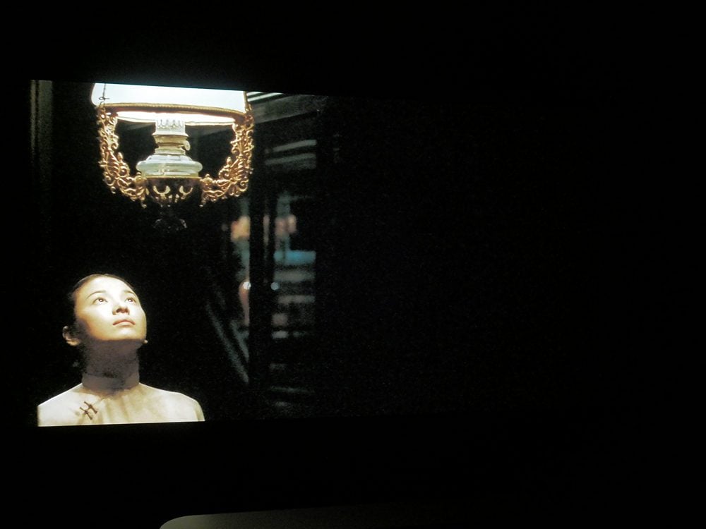 oświetlona lampą twarz kobiety, druga połowa ekranu ciemna