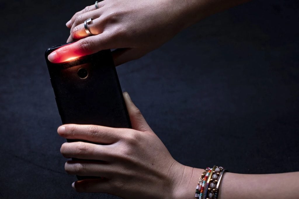 smartfon aparat jak pulsoksymetr kobieta przykłada palec do obiektywu