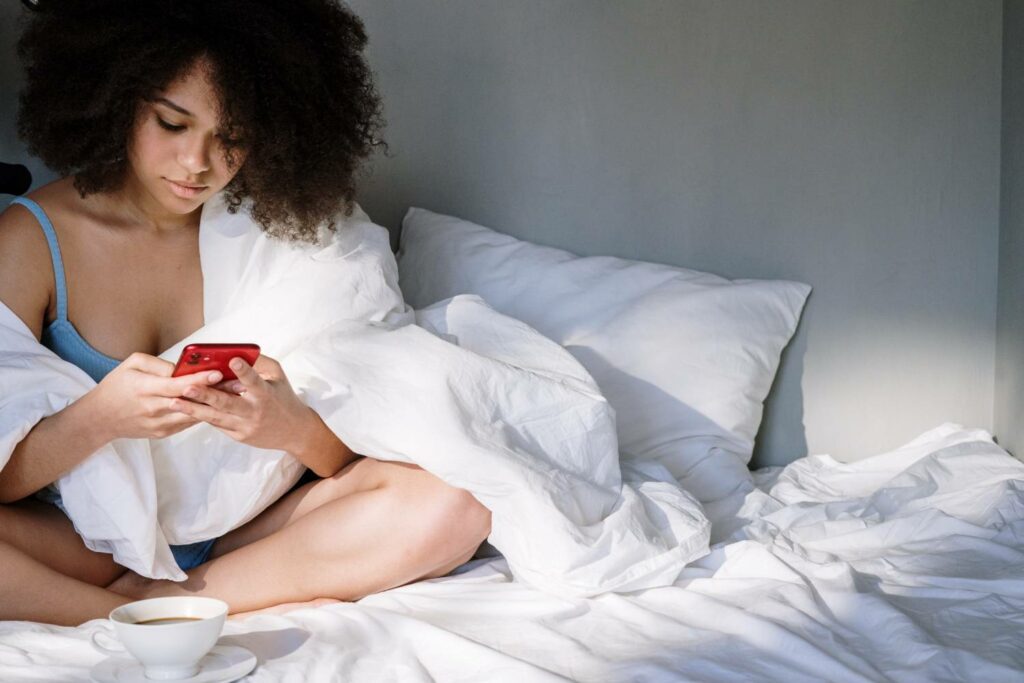kobieta przegląda smartfon w łóżku